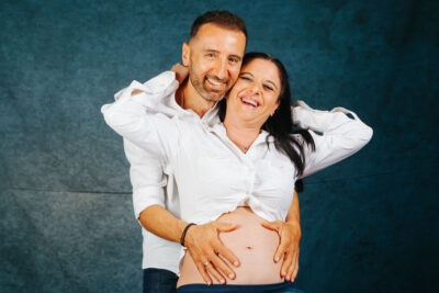 ζευγάρι άνδρας γυναίκα, αγκαλιά χαμογελαστοί στο φακό η γυναίκα είναι έγκυος